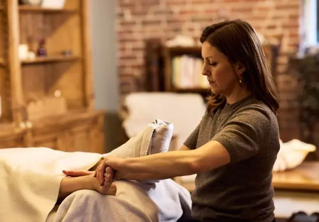 A woman massages a foot for Reflexology