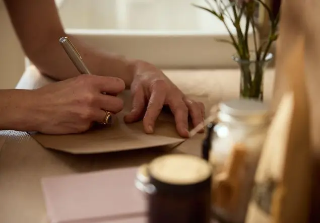 A woman's hands writing with a silver pen