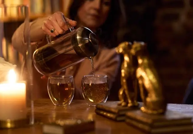A woman pours tea into two glass mugs