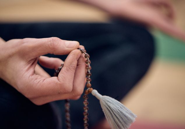 A woman's hands holding beads for yoga